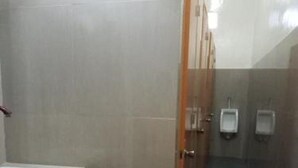 A public restroom with a white sink, a trash bin, and two urinals.