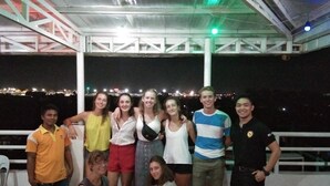 A group of people posing on an outdoor terrace with a view of the city at night.