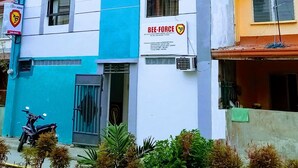 A multi-story building with a blue and white facade, a visible sign for 'Bee-Force', and a parked motorcycle.