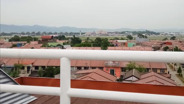 A view of a residential area with houses, a distant airport, and mountains in the background.