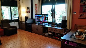 Una sala de estar con chimenea, televisor y comedor con mesa y sillas.