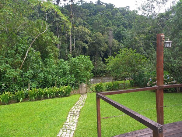 A garden with a paved path, wooden fence, and lush greenery.