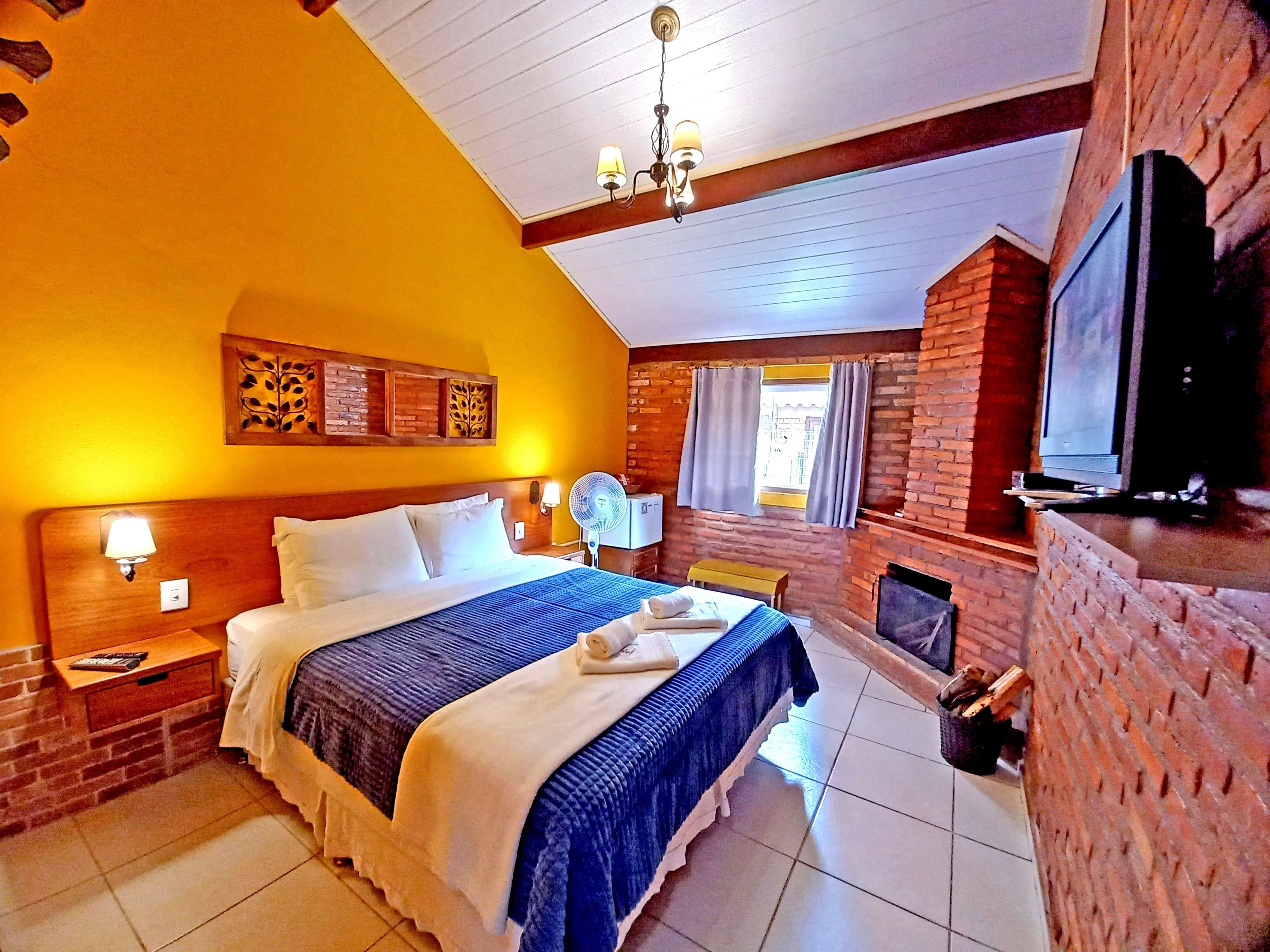 Habitación de hotel con una cama grande, televisión, chimenea y ventana con cortinas.