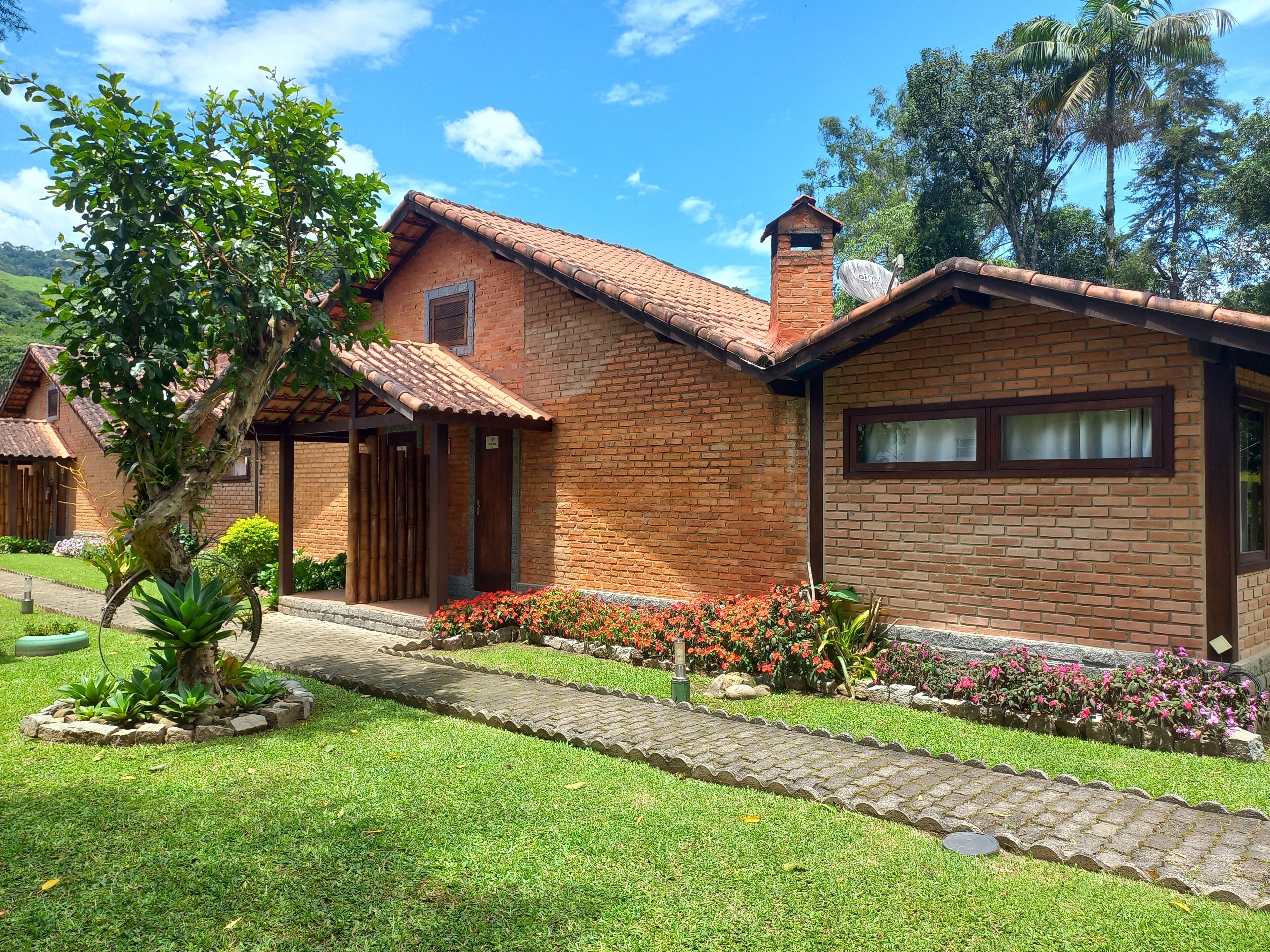 A brick building with a tiled roof, a small garden with flowers, and a pathway leading to the entrance.