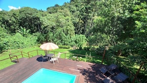 A wooden deck with a swimming pool, surrounded by lush greenery and a wooden fence. - Pousada Visconde de Mauá (Resende)