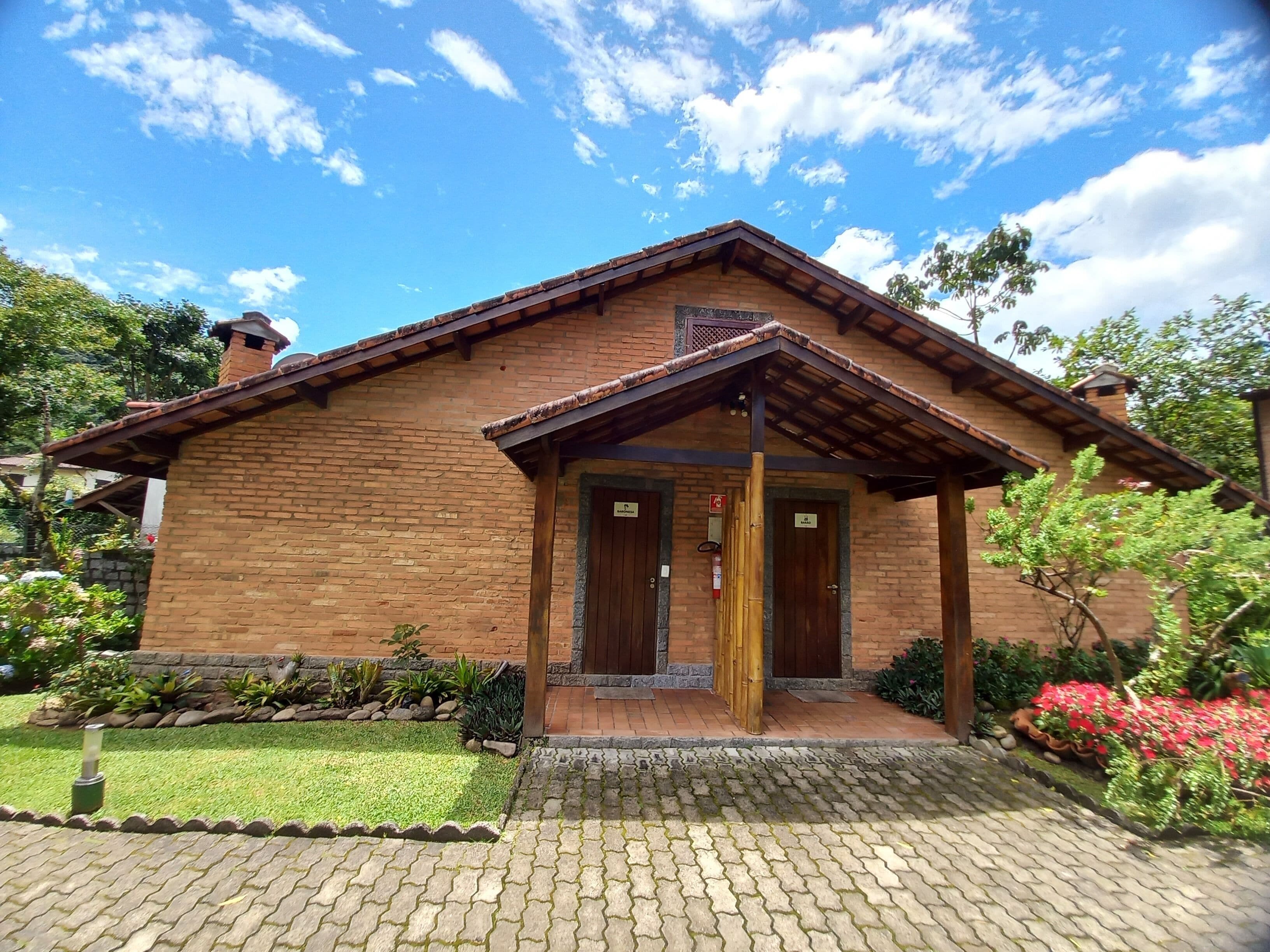 A brick house with a tiled roof, two wooden doors, and a small porch.