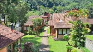 A cluster of traditional-style cottages with tiled roofs, surrounded by lush greenery and a well-maintained garden. - Pousada Visconde de Mauá (Resende)