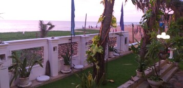 Varanda com vasos de plantas, vista para a praia e corrimão.