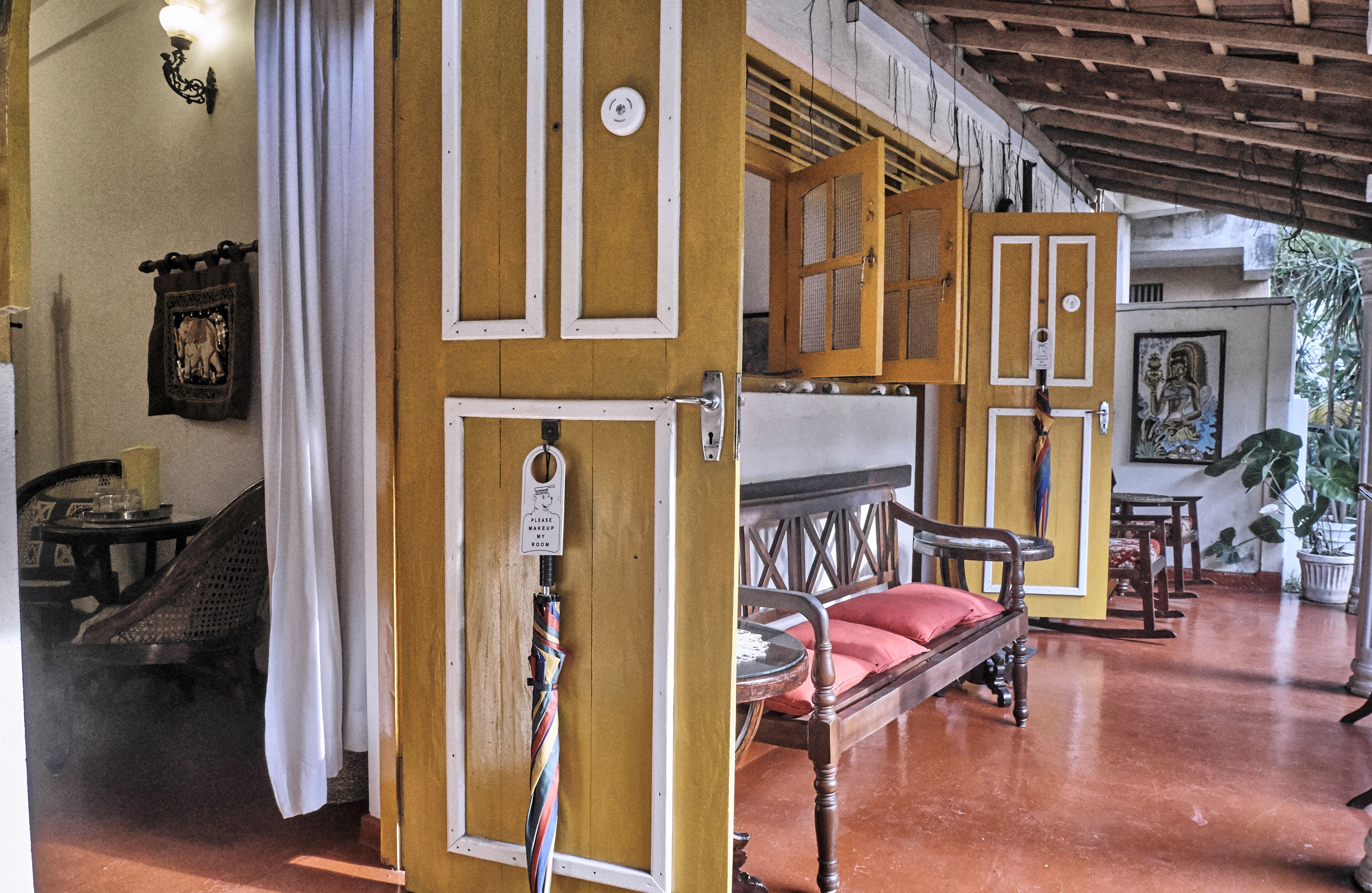 A traditional room with wooden doors, a bed with a red pillow, a small round table, and a chair.