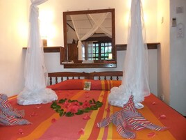 Una cama con dosel, un espejo y una ventana con vistas al verdor.