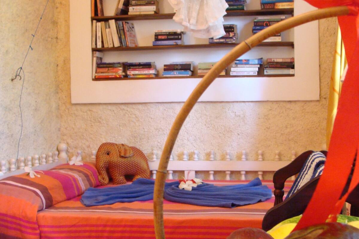 A room with a bed, a bookshelf, and a fruit basket.