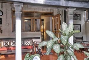 Decoração tradicional com móveis de madeira, uma planta grande e uma janela com cortinas.