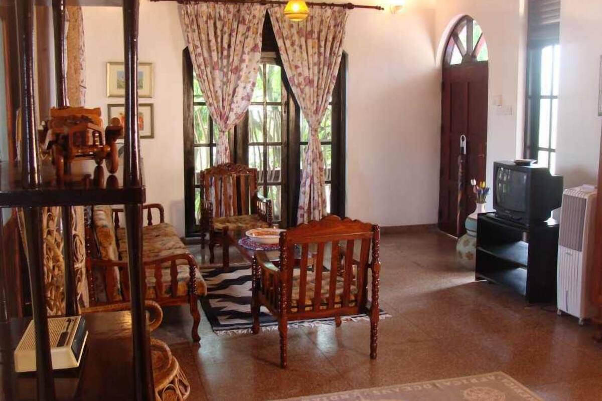 A cozy living room with wooden furniture, a television, and a large window with curtains.