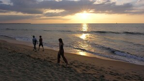 A beach with people walking along the shore during sunset. - The Icebear Guesthouse (Negombo)