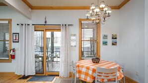 A dining area with a checkered tablecloth, a chandelier, and a view through the glass door. - Lake Life Getaway - Condo near downtown! (Douglas)