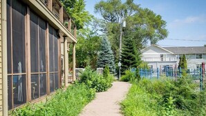 A pathway leading to a building with large windows and a fenced area with greenery. - Lake Life Getaway - Condo near downtown! (Douglas)