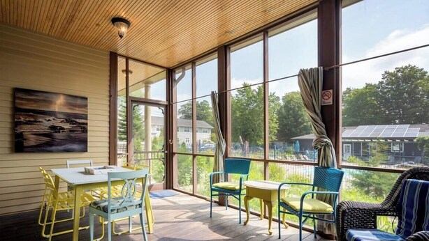 A sunlit room with large windows, a table, chairs, and a wicker sofa. - Lake Life Getaway - Condo near downtown! (Douglas)