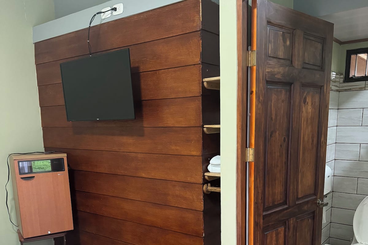 A bathroom with a wooden vanity, a toilet, and a shower area.