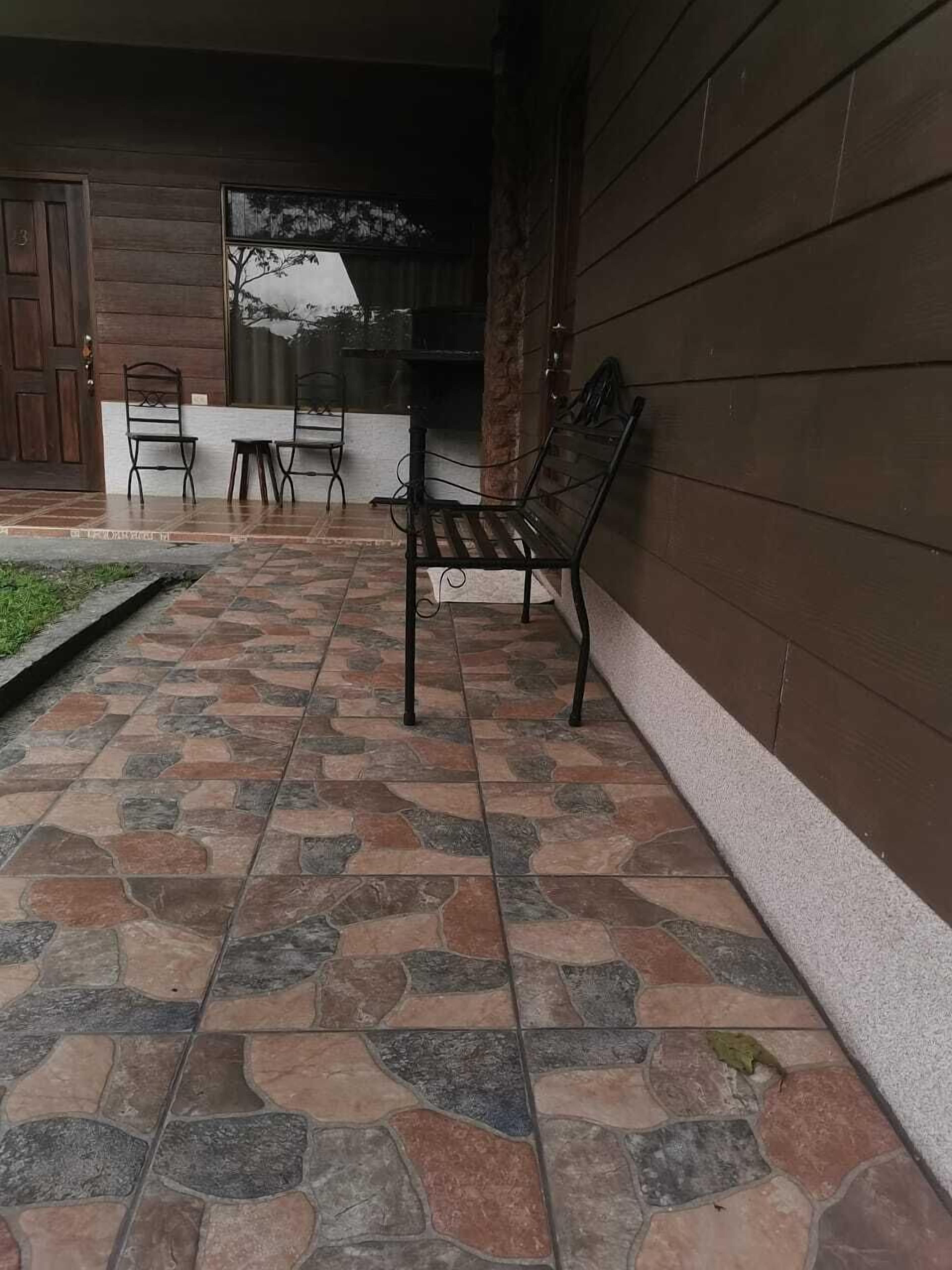 Un patio con suelo de losas de piedra, una puerta de madera y un banco.
