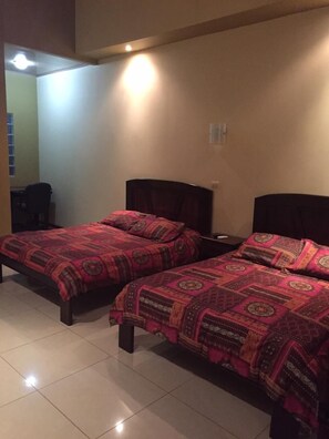 Une chambre avec deux lits, chacun agrémenté de draps à motifs, une chaise et une petite table.
