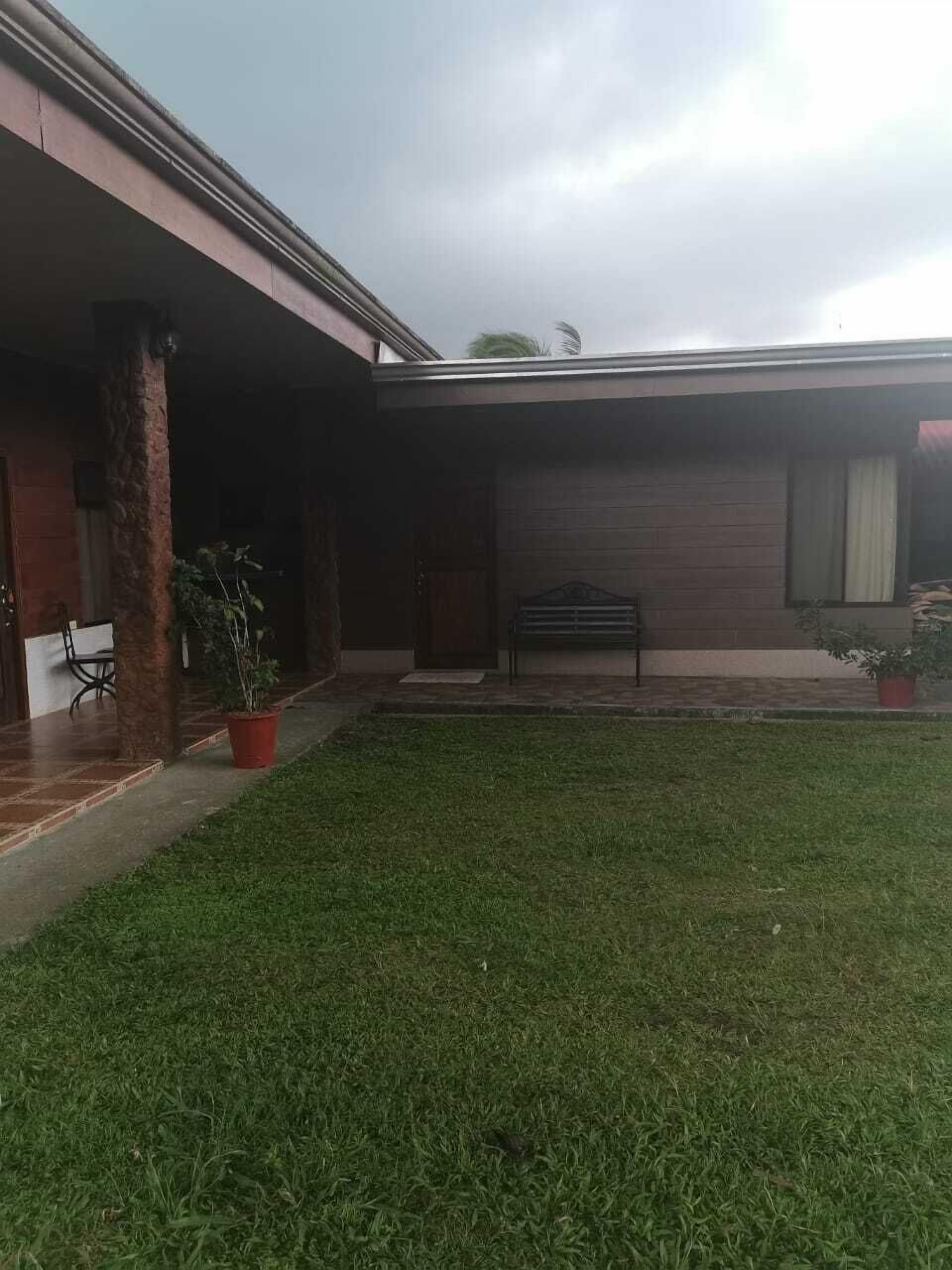 Uma casa com varanda coberta, gramado e coluna de tijolos.