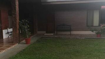 Uma casa com varanda coberta, gramado e coluna de tijolos.
