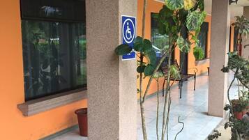 Un espacio al aire libre cubierto con señal de accesibilidad para sillas de ruedas, plantas en macetas y suelo de baldosas.