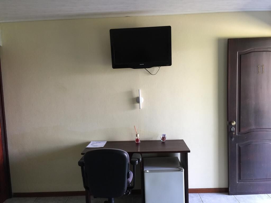 Una habitación con escritorio, silla, televisor y puerta.