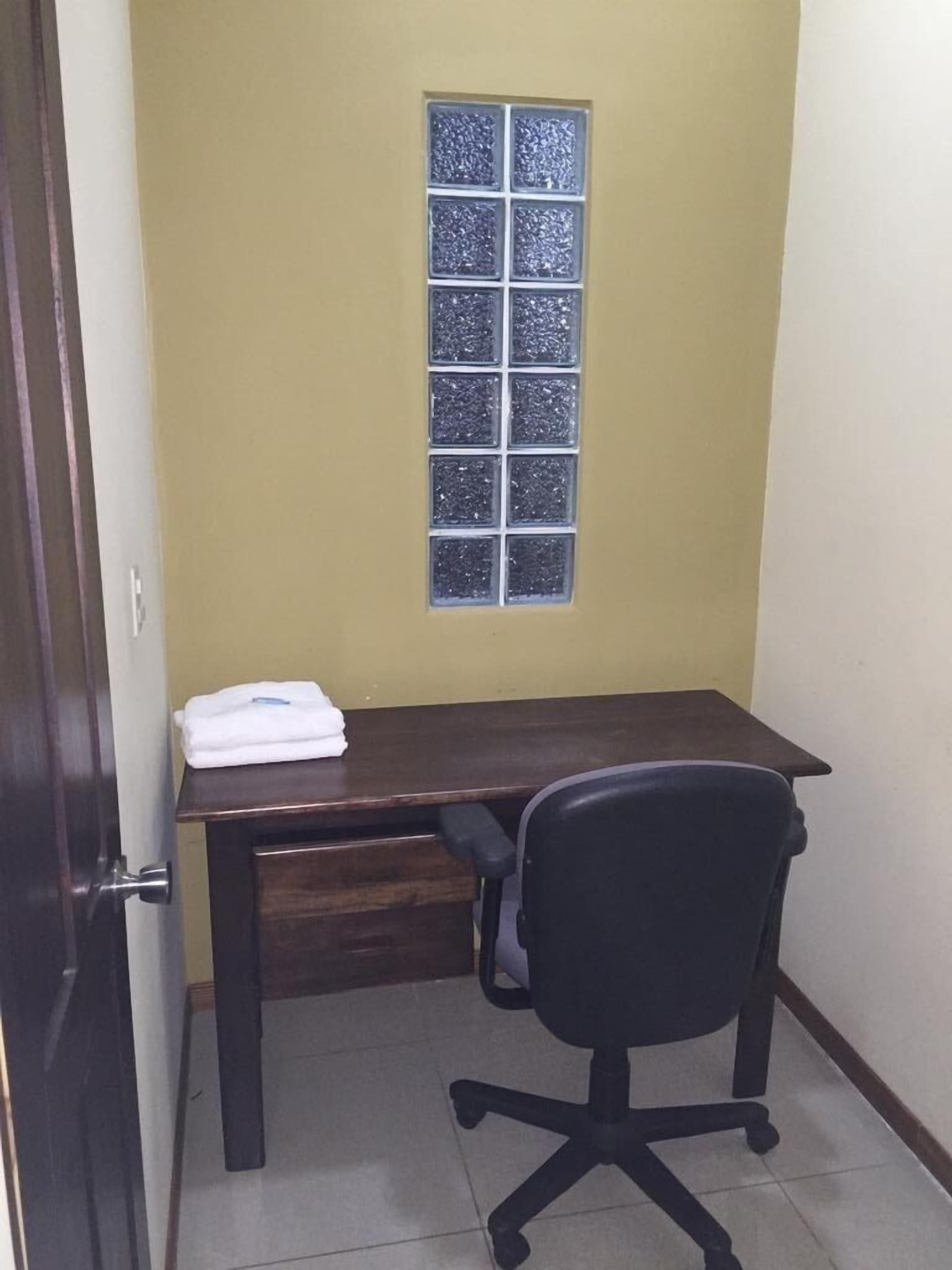 A small office space with a desk, chair, and a window with frosted glass.