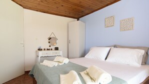 Ein Schlafzimmer mit einem Bett, einem Kleiderschrank, einem Nachttisch und zwei Wandbildern.