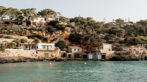 A coastal village with stone buildings, some with green shutters, situated on a hillside overlooking the sea. - Casa Sigrunella++with infinity pool (12x4m)++ in Cala Llombards (Cala Llombards)