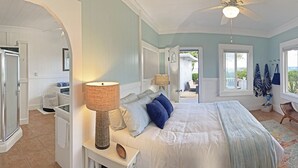 Un dormitorio con cama, mesita de noche, lámpara, ventana y vistas al exterior.