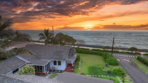 Una casa costera con vista al océano al atardecer.