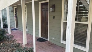 A building with a covered walkway, numbered doors, and a visible window.