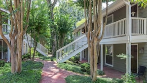 A pathway leading to a building with a staircase and a balcony.