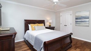 A bedroom with a wooden bed, a nightstand, a ceiling fan, and a framed picture on the wall.
