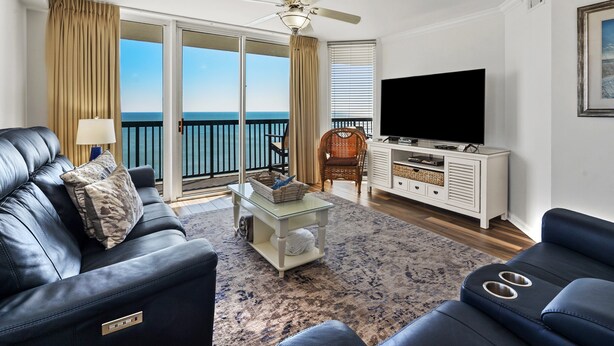 A living room with a sofa, a coffee table, a television, and a view of the ocean. - Ashworth 1809 4 Bedroom Condo by RedAwning (North Myrtle Beach)