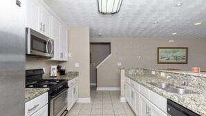 A modern kitchen with stainless steel appliances, granite countertops, and a large island with a sink.