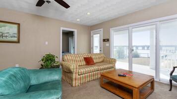 A living room with a teal sofa, plaid sofa, and a wooden coffee table.
