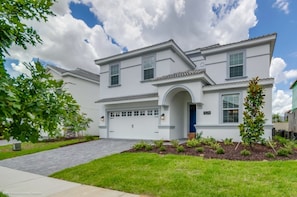A two-story house with a garage, a front entrance with an archway, and a well-maintained lawn. - Villa in Champions Gate Resort 2527 (Davenport)