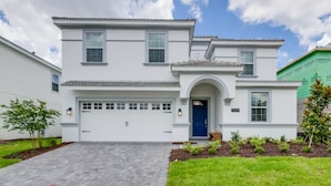 A two-story house with a white exterior, a blue door, and a garage. - Villa in Champions Gate Resort 2527 (Davenport)