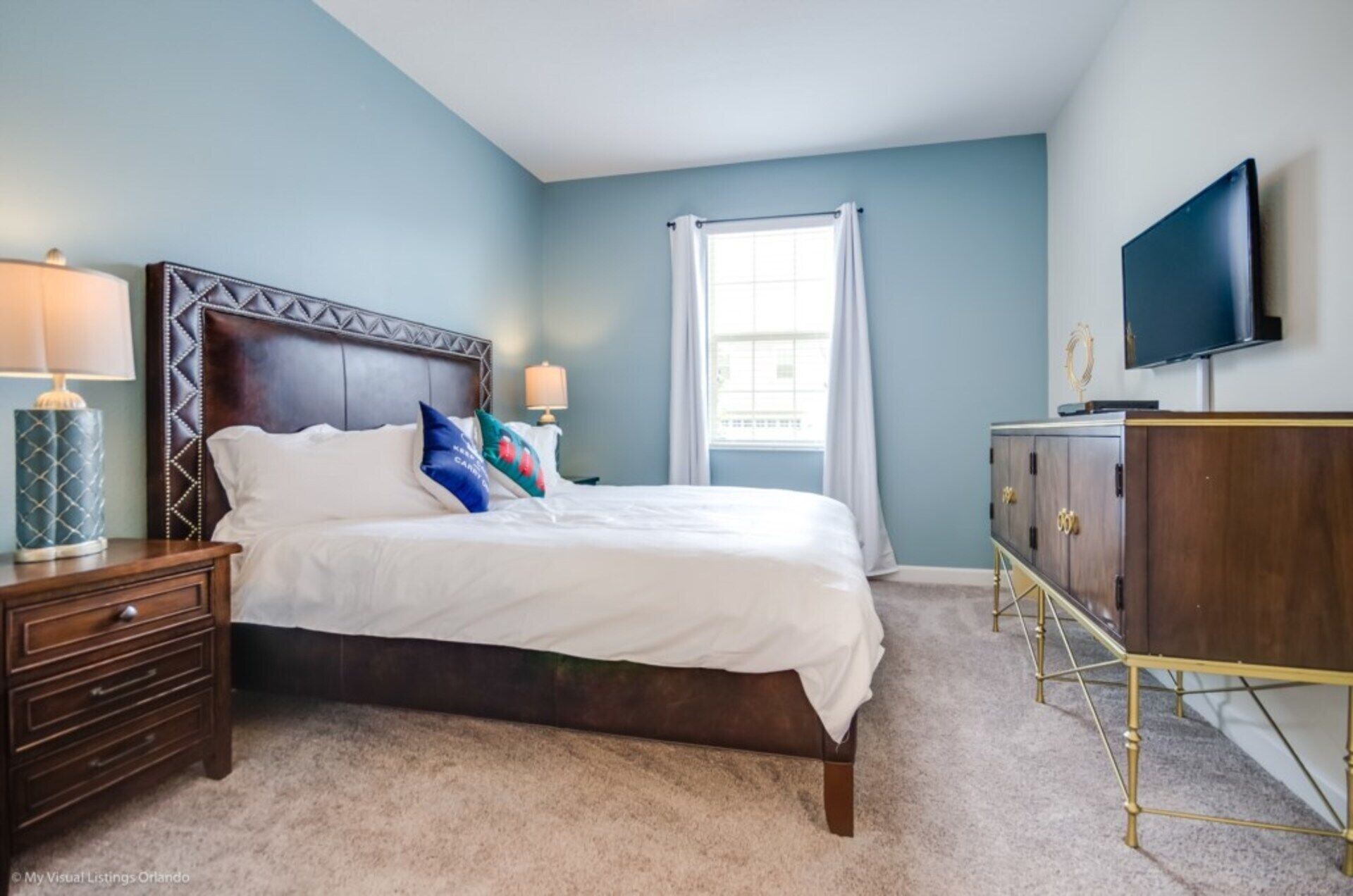 A bedroom with a bed, nightstands, a TV, and a dresser.
