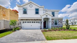 A two-story house with a garage, stone facade, and a well-maintained lawn. - Villa in Champions Gate Resort 2523 (Davenport)
