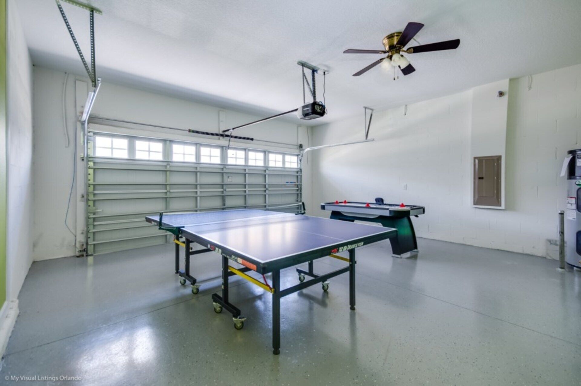 Une pièce spacieuse équipée d’une table de ping-pong, d’un baby-foot et d’un ventilateur de plafond.