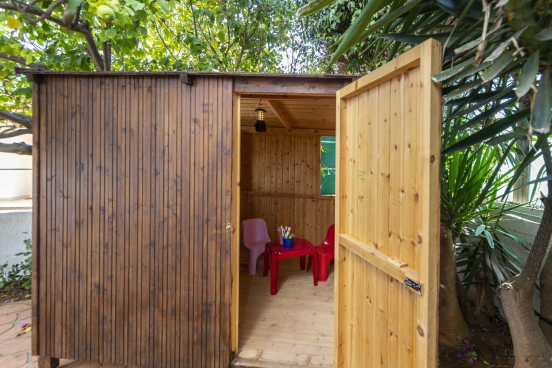 A wooden structure with a door open, revealing a small room with a table and chairs.