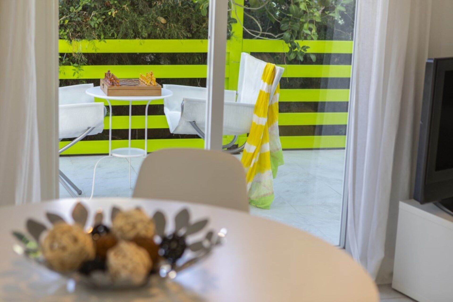 A dining area with a table set for two, a chessboard, and a chair with a yellow and white striped towel.