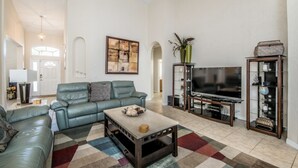 A spacious living room with a large sofa, a coffee table, a TV, and a decorative cabinet. - Beautiful Villa With Private Pool, Orlando Villa 1488 (Davenport)