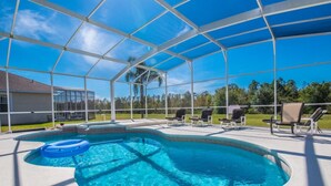 A covered swimming pool with a blue inflatable ring, surrounded by lounge chairs and a view of a house and trees. - Beautiful Villa With Private Pool, Orlando Villa 1488 (Davenport)
