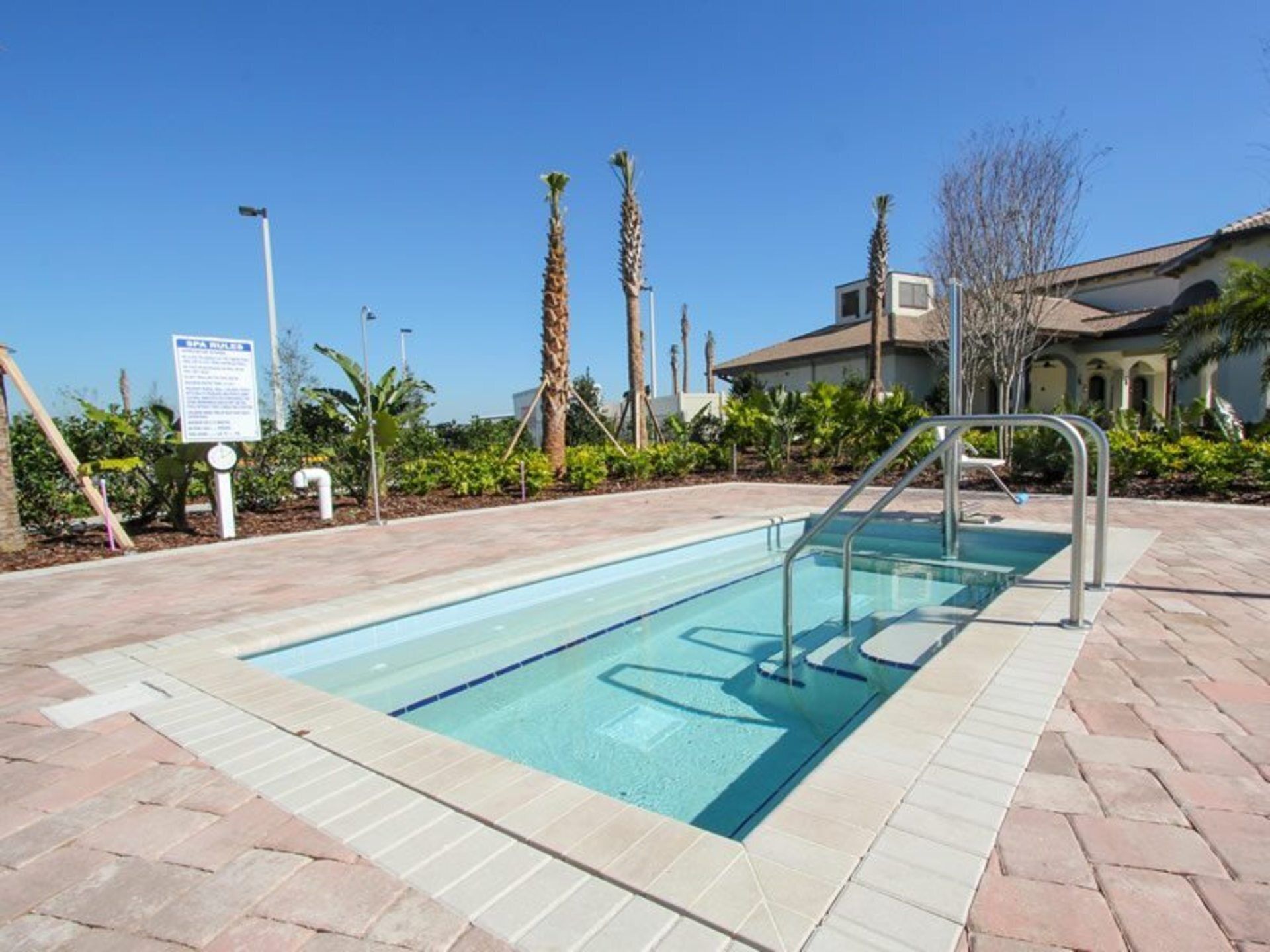 A rectangular swimming pool with a metal ladder and a signboard in the background.