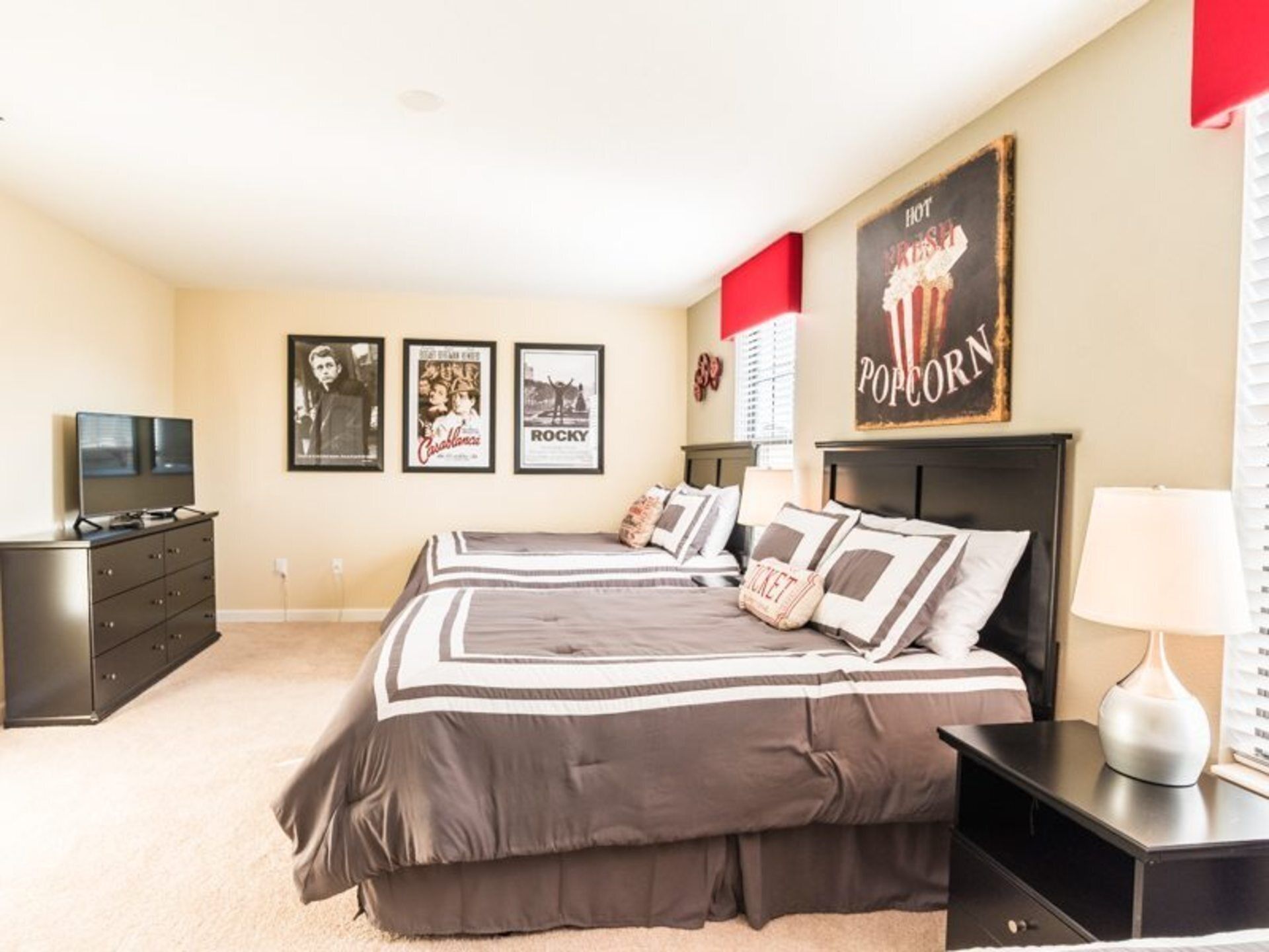 A bedroom with a large bed, a dresser, a TV, and framed movie posters on the wall.